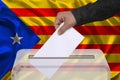 Male voter drops a ballot in a transparent ballot box on the background of the national flag of Catalonia, concept of state Royalty Free Stock Photo