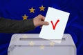 Male voter drops the ballot in a transparent ballot box against the background of the EU national flag, concept of state elections Royalty Free Stock Photo