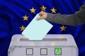 Male voter drops the ballot in a transparent ballot box against the background of the EU national flag, concept of state elections Royalty Free Stock Photo