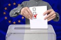 Male voter drops a ballot in a transparent ballot box against the background of the European Union national flag, concept of state Royalty Free Stock Photo