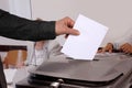 Male voter throws a ballot paper into a gray ballot box at a polling station in Germany, hand with paper close-up, concept of