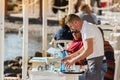 A male waiter clearing a table outdoors at a greek tavern in the waterfront of Mykonos, Greece