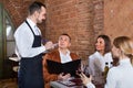 Male waiter taking order from visitors Royalty Free Stock Photo