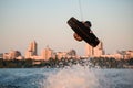 male wakeboarder making tricks and masterfully jumping over splashing wave on wakeboard Royalty Free Stock Photo