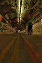 Male, walking past graffiti covered walls. Leake Street arches, Lambeth, London. Dutch tilt view.