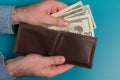 Men`s hands hold a leather wallet with dollar bills. Royalty Free Stock Photo