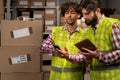Male warehouse multiethnic workers checking inventory and consulting each other about distribution of goods. Concept of Royalty Free Stock Photo