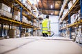 Male warehouse worker pulling a pallet truck. Royalty Free Stock Photo