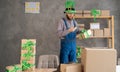 male warehouse worker seller in leprechaun hat, small stock business owner holding smartphone, using mobile app scanning Royalty Free Stock Photo