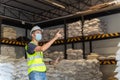 A male warehouse worker wear a mask use a laptop inspecting chemical products in alum or chemical warehouse storage. International