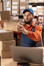 Male warehouse worker working on laptop at storage checking orders. Royalty Free Stock Photo