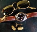 Male watch, cuff buttons and sunglasses on the leather top desk