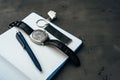 Male watch and notepad on dark grey table