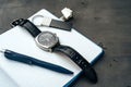 Male watch and notepad on dark grey table