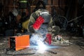 A male welder in a welding mask works with an arc electrode in his garage. Welding, construction, metal work