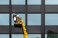 Male window cleaner cleaning glass windows on modern building high in the air on a lift platform. Worker polishing glass high in Royalty Free Stock Photo