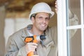 Male window fitter holding cordless drill