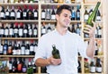 Male wine expert holding wine bottles in winery section