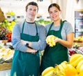 Male and woman sellers offering bananas standing in fruit and vegetable section of supermarket Royalty Free Stock Photo