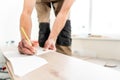 Male worker applies markings to the Board for cutting with a electrofret saw. installing new wooden laminate flooring Royalty Free Stock Photo