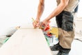 Male worker applies markings to the Board for cutting with a electrofret saw. installing new wooden laminate flooring Royalty Free Stock Photo