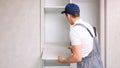 Male worker assembles light wardrobe attaching shelves Royalty Free Stock Photo