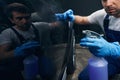 Car mechanic using cleaning spray on automobile door
