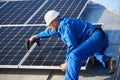 Electrician mounting solar panel on roof of modern house