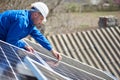 Electrician mounting solar panel on roof of modern house Royalty Free Stock Photo