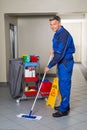 Male Worker With Broom Cleaning Corridor