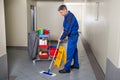 Male Worker With Broom Cleaning Corridor Royalty Free Stock Photo