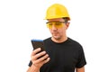 Male worker or builder in yellow helmet using smartphone isolated on white background. Construction concept Royalty Free Stock Photo