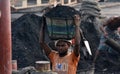 male worker is busy to loading a coal truck on his head . He is working without any safety equipment.