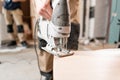 Male worker cuts the laminate Board with an electrofret saw. installing new wooden laminate flooring. concept of repair Royalty Free Stock Photo