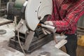 A male worker cuts a stainless steel pipe on a special machine for vertical sawing of metal parts for industrial use. Making Royalty Free Stock Photo