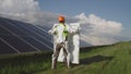 Man in exoskeleton taking solar panel from colleague