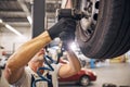 Professional mechanic repairing car wheel disk in garage Royalty Free Stock Photo