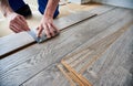 Male worker hands drawing line on laminate wood plank.