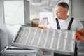 A male worker holds an air filter for air conditioning in an office space. Installation of an air conditioner. Royalty Free Stock Photo