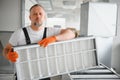 A male worker holds an air filter for air conditioning in an office space. Installation of an air conditioner. Royalty Free Stock Photo