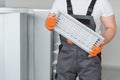 A male worker holds an air filter for air conditioning in an office space. Installation of an air conditioner. Royalty Free Stock Photo