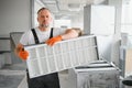 A male worker holds an air filter for air conditioning in an office space. Installation of an air conditioner. Royalty Free Stock Photo