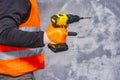 Male worker holds a close-up electric cordless screwdriver in his hands against the background of a construction tool and a Royalty Free Stock Photo