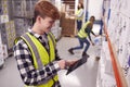 Male Worker Inside Busy Warehouse Checking Stock On Shelves Using Digital Tablet Royalty Free Stock Photo