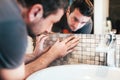 male worker installing ceramic mosaic tiles on bathroom walls