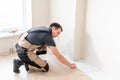 Male worker installing new wooden laminate flooring on a warm film foil floor. infrared floor heating system under Royalty Free Stock Photo