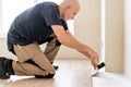 Male worker installing new wooden laminate flooring on a warm film foil floor. infrared floor heating system under Royalty Free Stock Photo