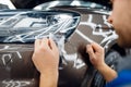Worker installs protection film on car hood Royalty Free Stock Photo