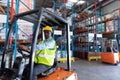 Male worker looking at camera while driving forklift in warehouse