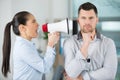 male worker oblivious to female colleague shouting through megaphone